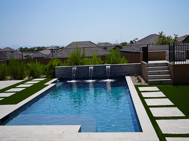 Three fountains built into the wall with an extended deck and pavers.